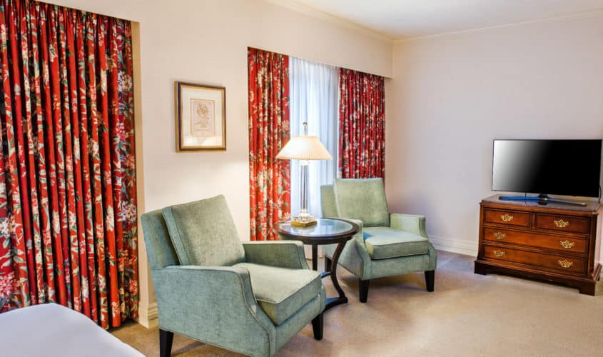 Seattle boutique hotel accessible sitting area with large windows two green chairs and dark wood furniture.