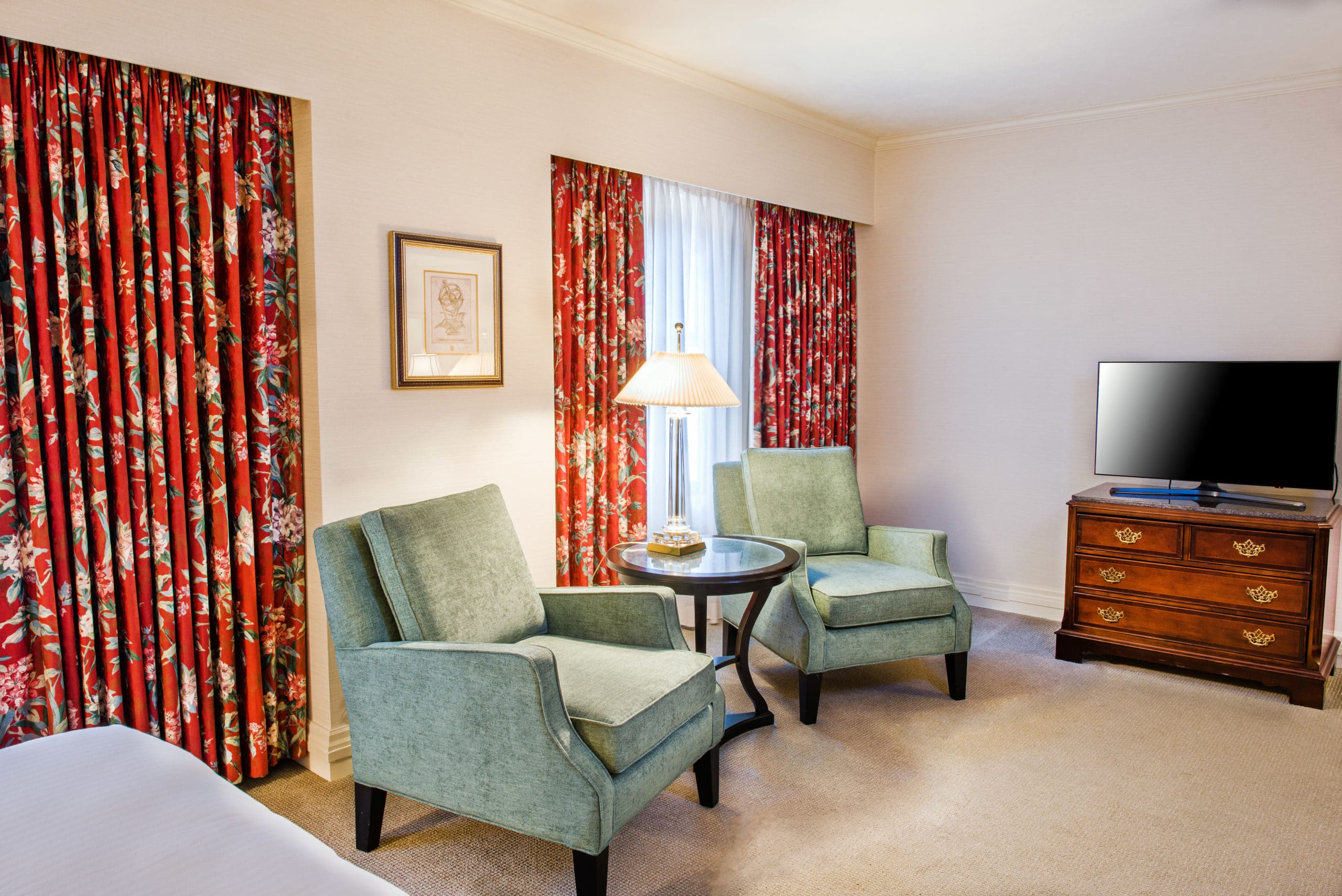 Seattle boutique hotel accessible sitting area with large windows two green chairs and dark wood furniture.