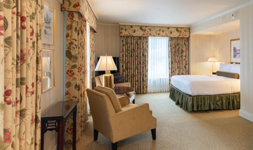 The Deluxe Queen guestroom of our historic hotel in Seattle with large windows and high ceilings.