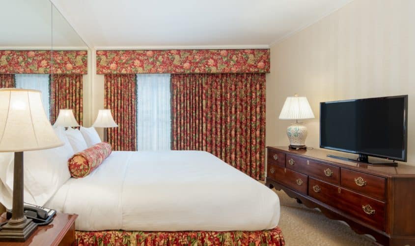 King Guest Room with red floral drapes and dark wood dresser with a tv on it in downtown Seattle