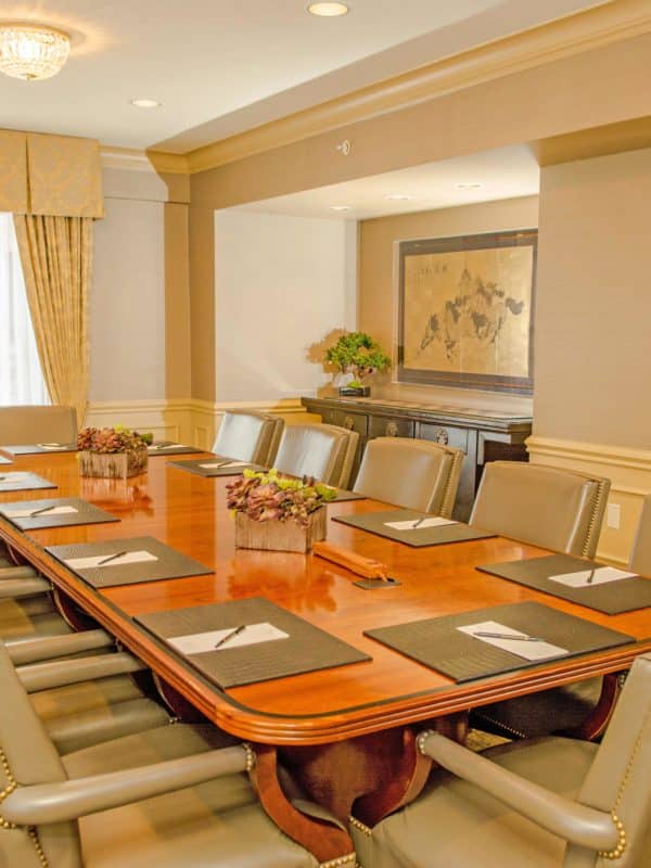 Board Room at Mayflower Park Hotel with wood table, plush seats & a window to bring in natural light