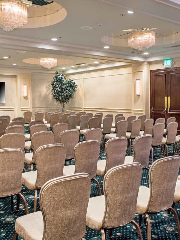 The Plymouth Room, a large event space at our Seattle hotel featuring chairs in rows & large television screen