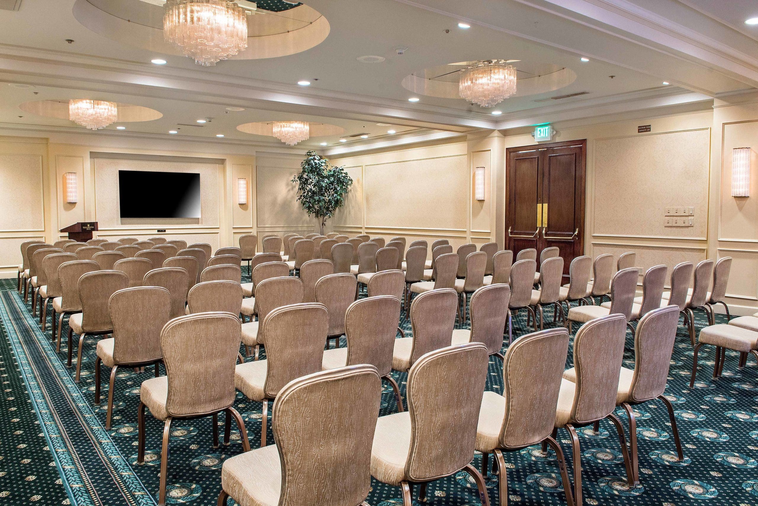 The Plymouth Room, a large event space at our Seattle hotel featuring chairs in rows & large television screen