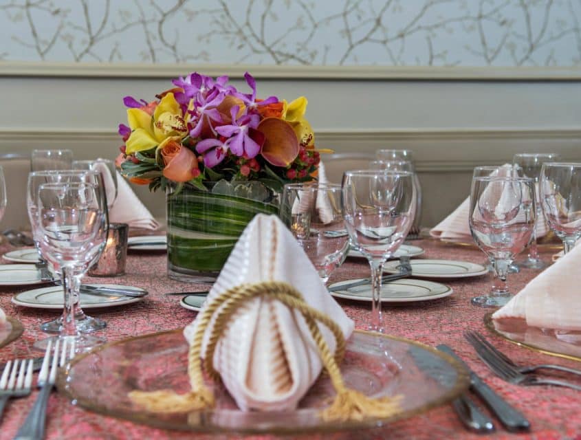 Table set for a sit down event with a vibrant floral center piece in the Rose Room in downtown Seattle