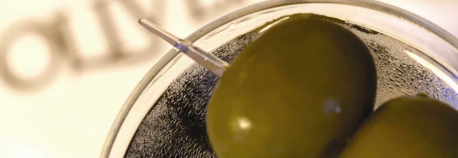 Two olives in a martini glass on top of a napkin for Oliver's Lounge in Seattle