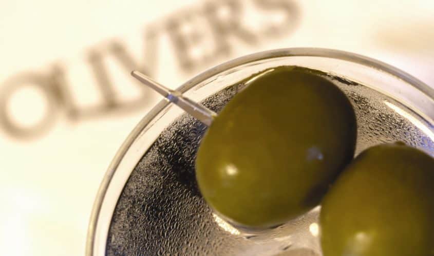 Two olives in a martini glass on top of a napkin for Oliver's Lounge in Seattle