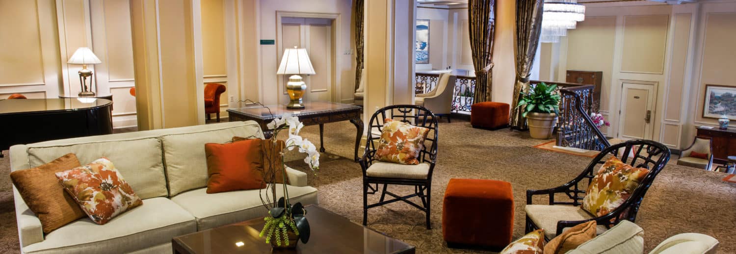 Side view of the fireside room with sofa, piano and stairs leading to the Mayflower Park Hotel lobby