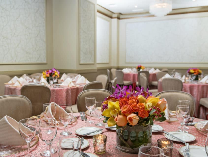 Tables set up in the Rose room with floral arrangements with set tables at Mayflower Park Hotel