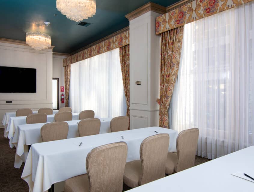 the green room with rectangle tables, chairs, and a TV