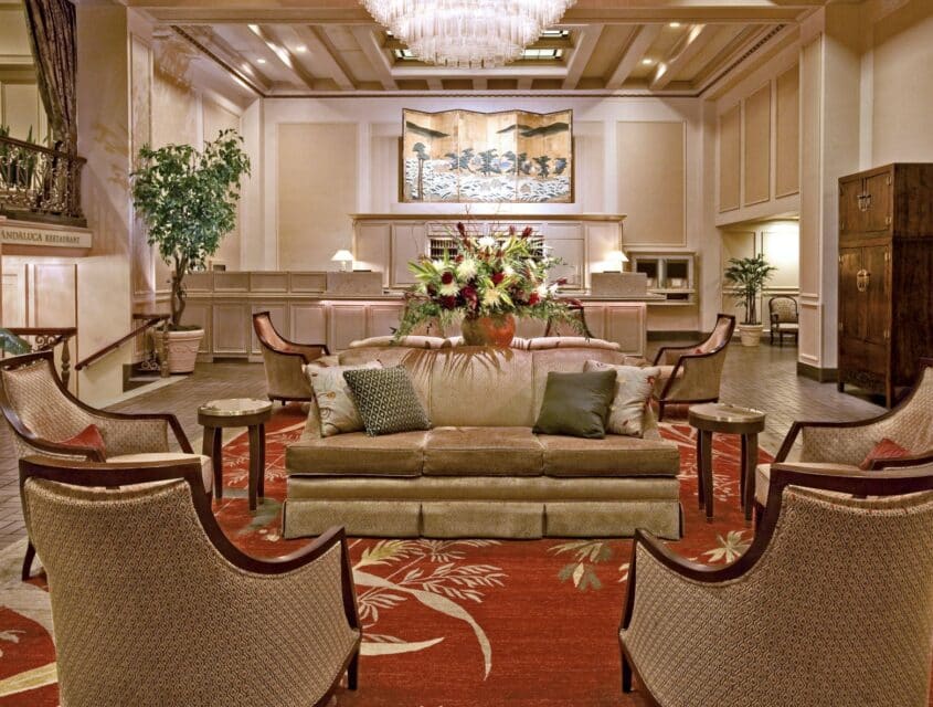 Soft, neutral-colored furniture in an award winning historic Seattle hotel with green plants, and elegant decor.